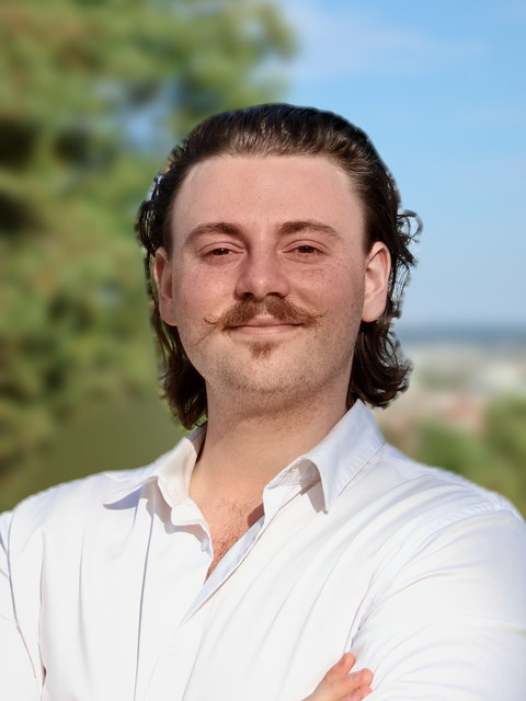 Maxence, associé de Mediassemblage, chemise blanche et moustache