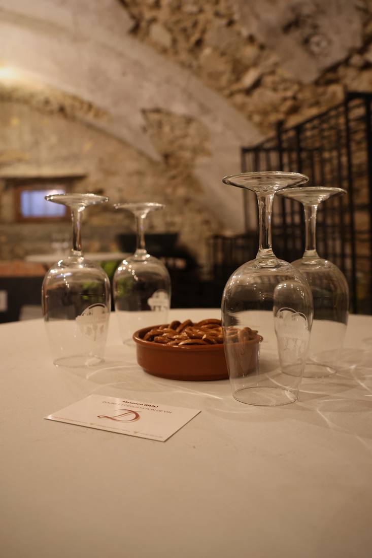 Verres à dégustation retournés sur une table nappée de blanc, sous une voûte de pierre
