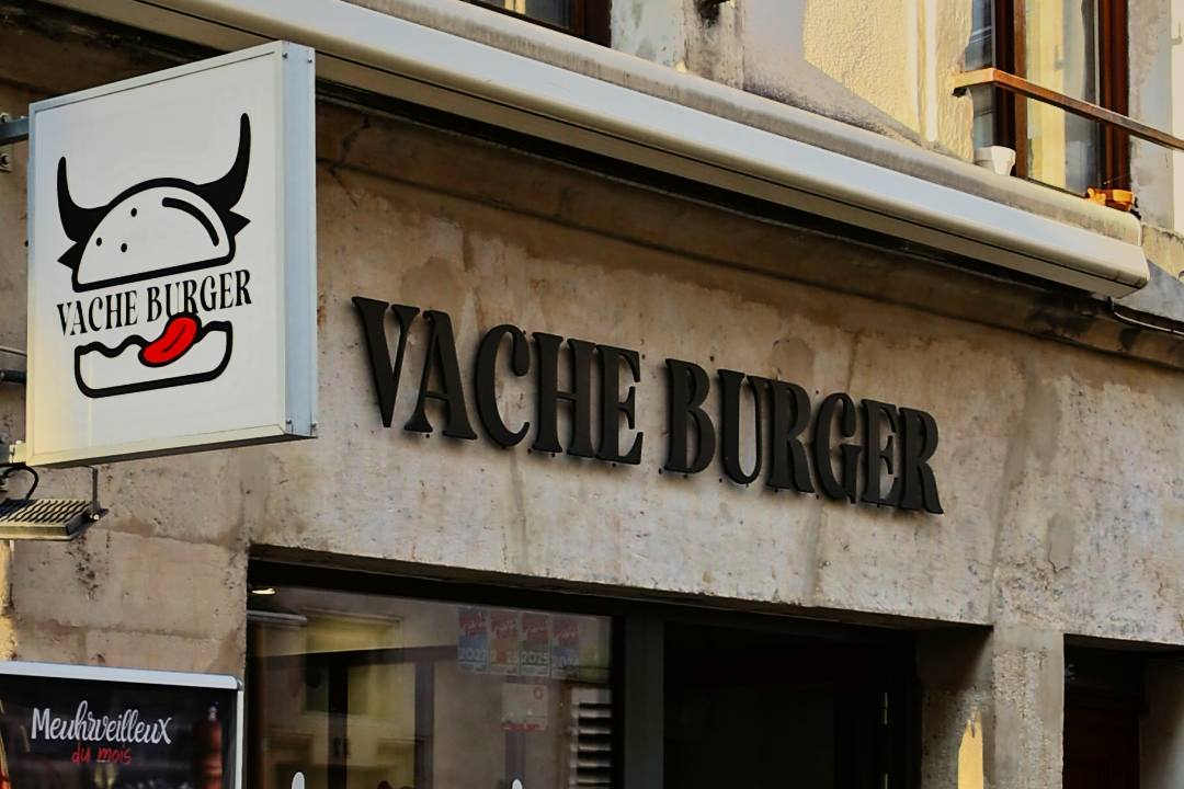 La façade de Vache Burger, rue de la Primatiale à Nancy : l'enseigne et le nom en lettres noires sur la pierre