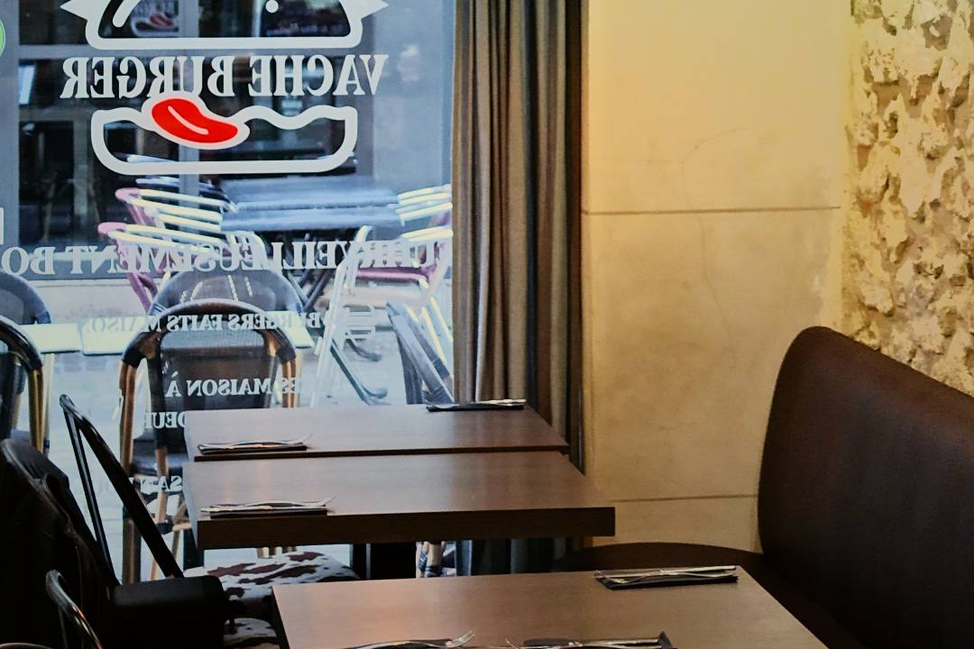 La salle de Vache Burger, les tables dressées le long de la vitrine au logo du restaurant