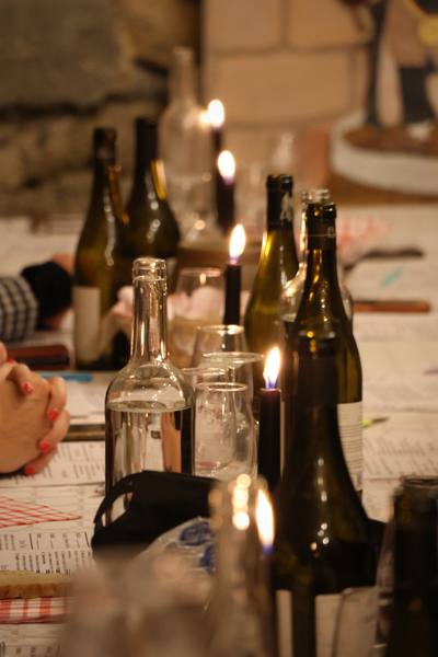 Bouteilles de vin et bougies allumées sur une longue table, dans une cave voûtée