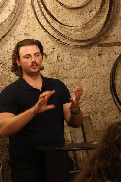 Maxence, de Mediassemblage, explique un vin pendant un cours d'œnologie en cave voûtée