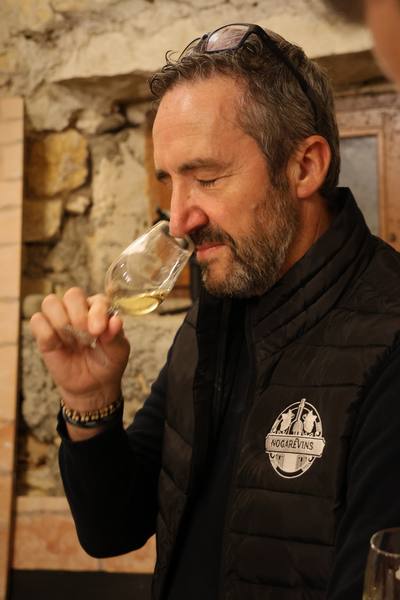 Un membre des Nogarévins sent son verre de vin blanc